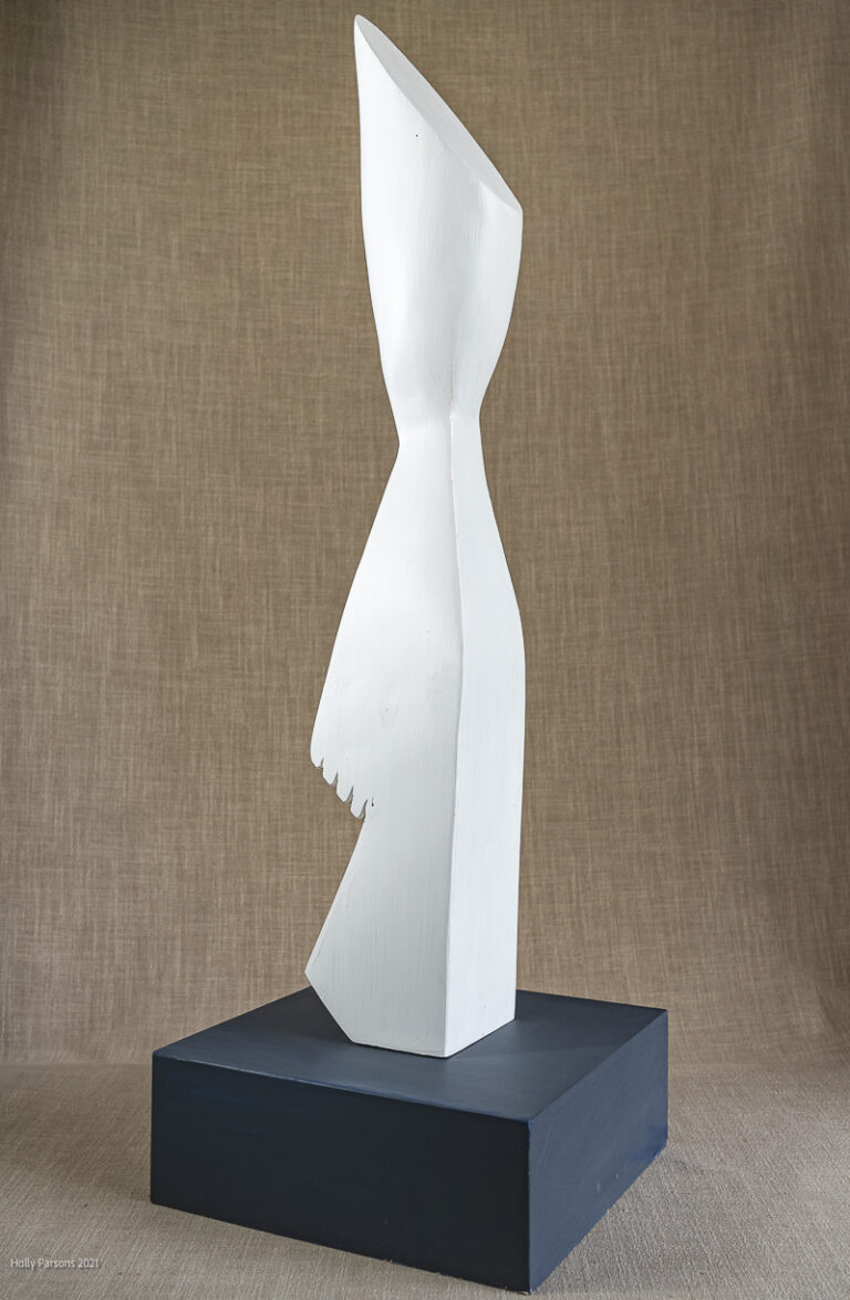 Wood carving sculpture of abstract figure painted white on a grey wood base